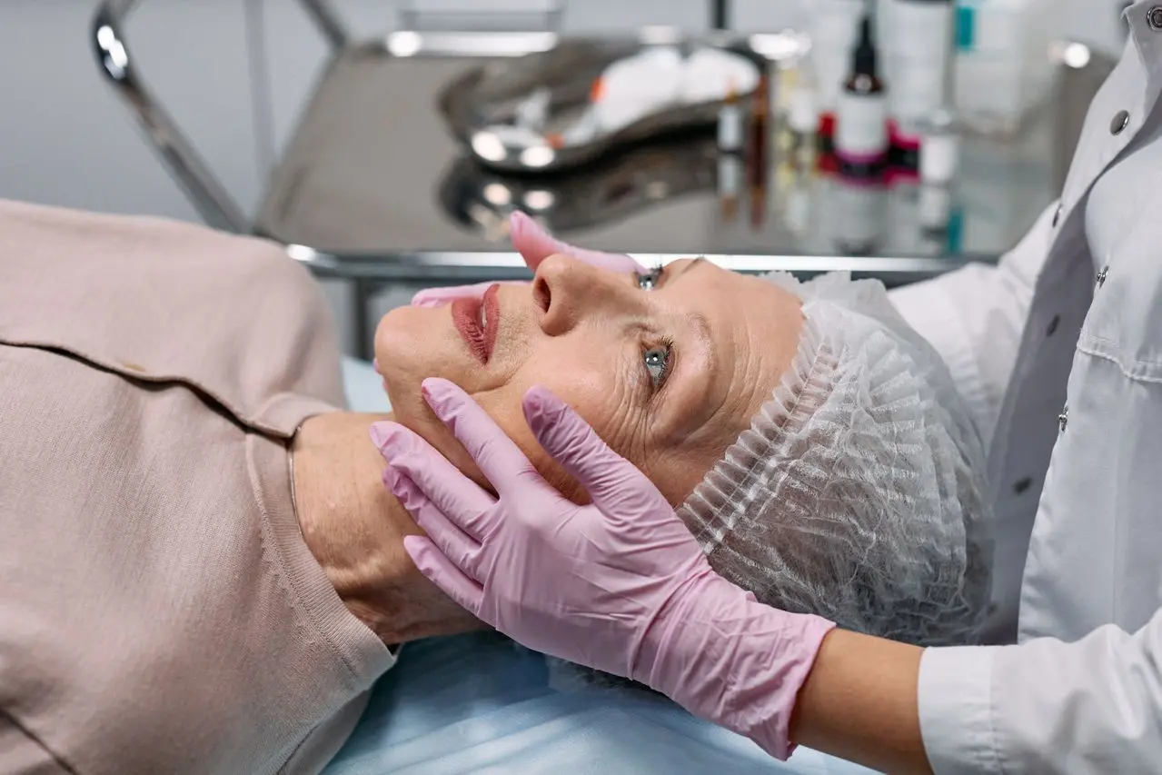 Woman on a surgical table while a surgeon examines her face